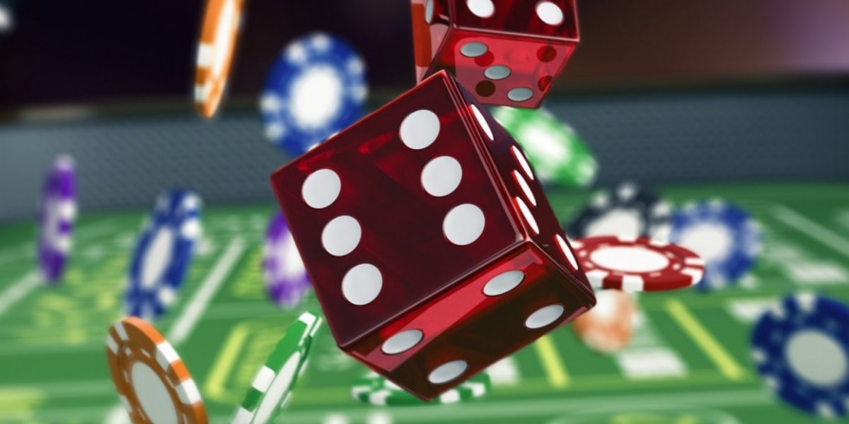 The image depicts a dynamic casino scene focused on dice and gambling elements. In the foreground, two large red dice are shown mid-roll, with white dots clearly visible. The dice appear to be floating above a green surface, likely representing a craps table or other casino game surface. Surrounding the dice are various casino chips in different colors, including blue, white, red, and green. Some poker chips are stacked while others are scattered across the table. In the background, there's a blurred view of additional casino elements, creating depth and atmosphere. 